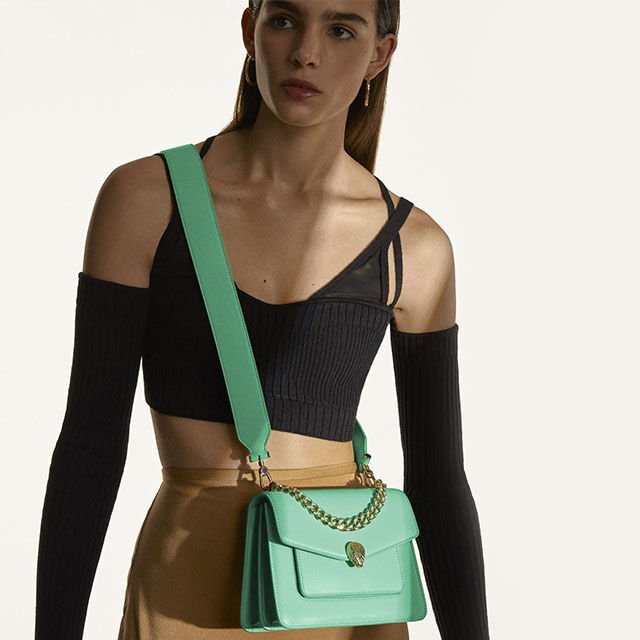 Model wearing a Serpenti Forever Maxi Chain crossbody bag in green nappa leather with chain handle.