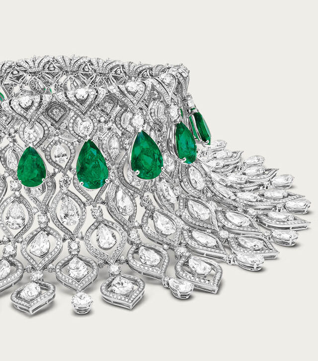 Eden High Jewellery platinum necklace with emeralds and diamonds, Bulgari logo backdrop, close up