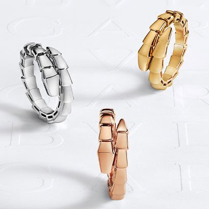Serpenti Viper single-coil rings in plain white, yellow and rose gold, against a white Bulgari logo backdrop.
