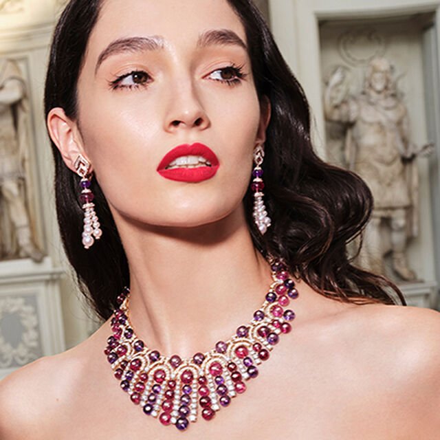 Model wearing a Barocko High Jewellery yellow gold necklace and earrings with amethyst and pink tourmaline beads, pearls and diamonds.