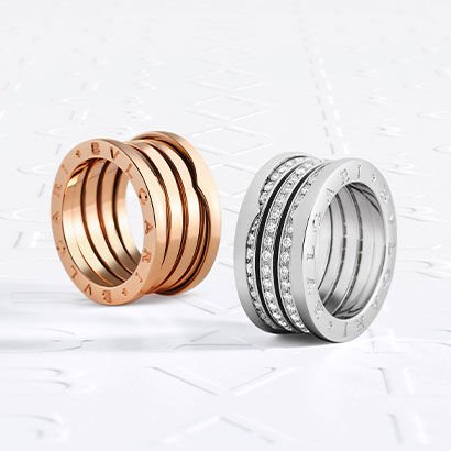 B.zero1 rose gold ring and B.zero1 white gold ring with diamonds on the spiral, against a logo backdrop.