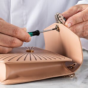 Craftsman assembling the snakehead closure of the Serpenti Forever Laser cut bag in pink calf leather. Craftsman assembling the snakehead closure of the Serpenti Forever Laser cut bag in pink calf leather.