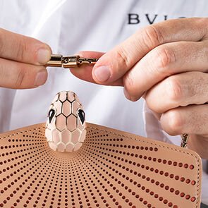 Craftsman assembling the chain strap of the Serpenti Forever Laser cut bag in soft pink calf leather. Craftsman assembling the chain strap of the Serpenti Forever Laser cut bag in soft pink calf leather.