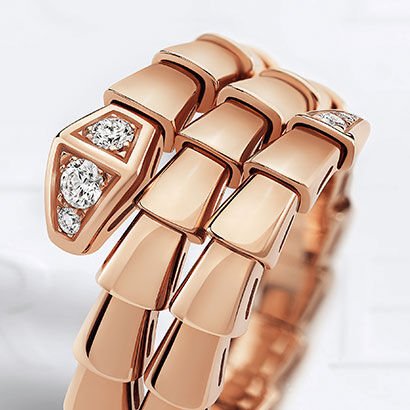 Serpenti Viper double-coil ring in rose gold with diamonds on the head, against a white backdrop.