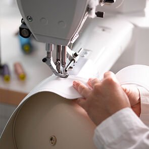 Craftsman sewing together white calf leather panels during the making of the Serpenti Ellipse bag. Craftsman sewing together white calf leather panels during the making of the Serpenti Ellipse bag.