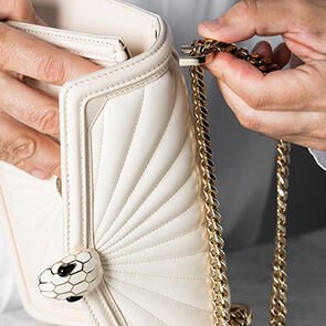 Craftsman assembling the chain strap of the Serpenti Diamond Blast Sunshine Quilted bag, close up.