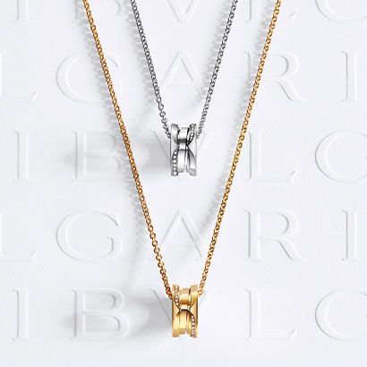 B.zero1 pendant necklaces in white and yellow gold set with pavé diamonds on the edges, against a logo backdrop.