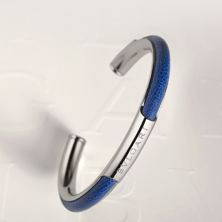 Two-headed Serpenti bracelet in golden karung skin on white Bvlgari logo backdrop. Two-headed Serpenti bracelet in golden karung skin on white Bvlgari logo backdrop.