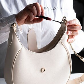 Craftsman assembling the snakehead closure of the Serpenti Ellipse bag in white calf leather, close up. Craftsman assembling the snakehead closure of the Serpenti Ellipse bag in white calf leather, close up.