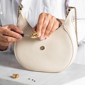 Craftsman assembling the snakehead closure of the Serpenti Ellipse bag in white calf leather Craftsman assembling the snakehead closure of the Serpenti Ellipse bag in white calf leather