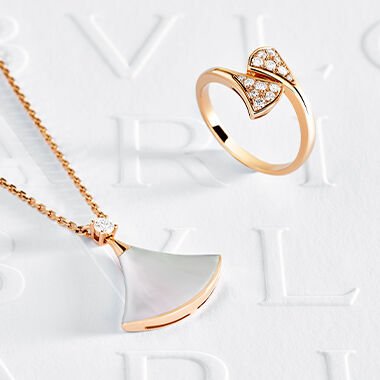 Hands wearing Divas' Dream rose gold bracelet and rings with diamonds and hard stones and other Bvlgari jewels.