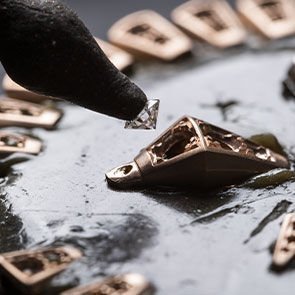 Setting of a diamond into a gold scale of the Serpenti Viper bracelet, other scales in the background. Setting of a diamond into a gold scale of the Serpenti Viper bracelet, other scales in the background.