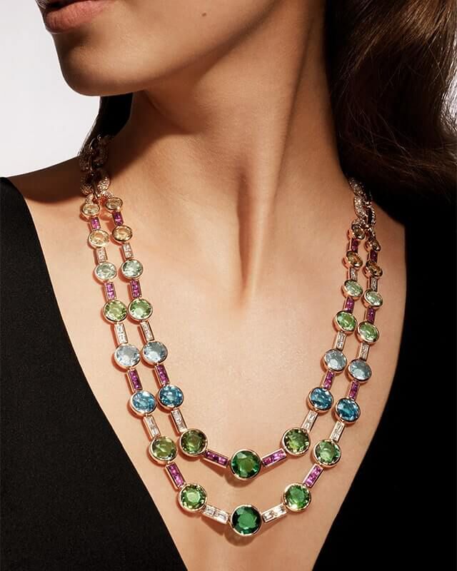 Model wearing the Eden High Jewellery rose gold necklace with blue-green hued coloured gems, close up.