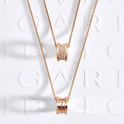 B.zero1 rose gold pendant necklaces, one with diamond pavé on the spiral, against a white logo backdrop.