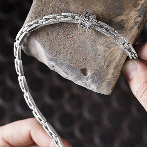 Craftsman holding the Bulgari B.zero1 Rock Chain white gold necklace fully set with diamonds, close-up.