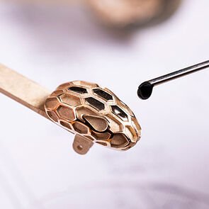 Snakehead decor enamelled by hand during the making of the Serpenti Forever sunglasses, close-up.
