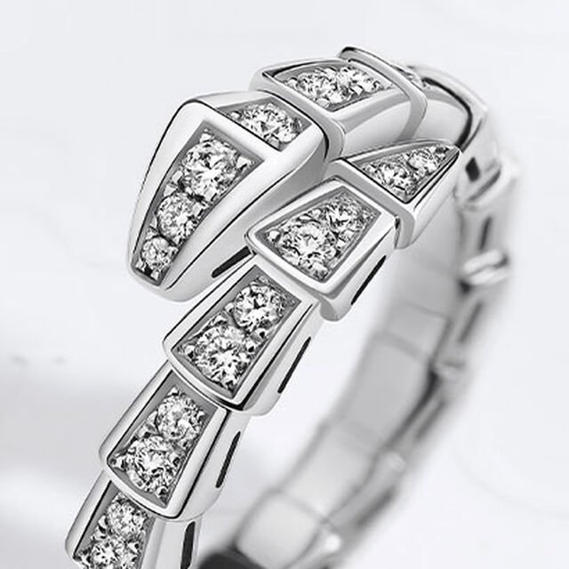 Serpenti Viper single-coil ring in white gold fully set with diamonds, against a white background.
