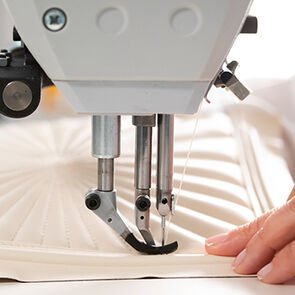 Craftsman sewing the radial quilted pattern of the Serpenti Diamond Blast Sunshine bag, close up.