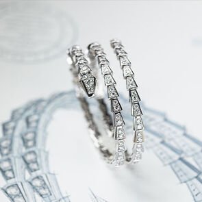 Serpenti Viper two-coil bracelet in white gold with diamonds, placed on a sketch of the same jewel.