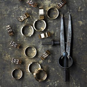Several gold elements of the B.zero1 Rock ring to be assembled and a crafting tool, close-up.