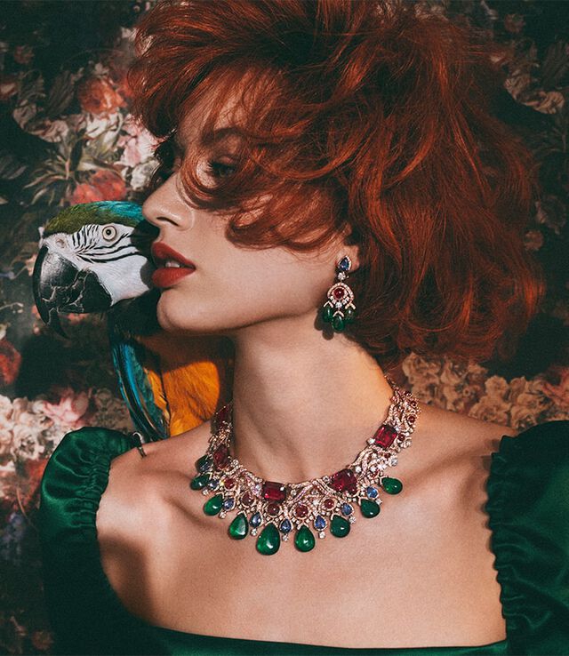 Model wearing two necklaces from the Cinemagia High Jewelry collection with emeralds and tourmalines.
