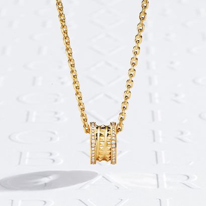 B.zero1 Rock yellow gold pendant necklace with studs and diamonds on the edges, against a white logo backdrop.