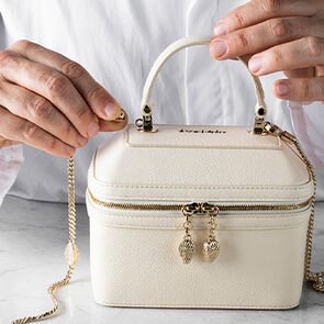 Craftsman attaching the chain strap to the Serpenti Jewellery box bag in white calf leather, close up.