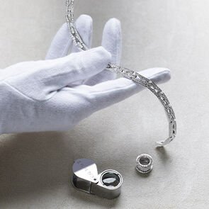 Hands with white gloves holding the B.zero1 Chain white gold necklace with diamonds, pendant on the side.