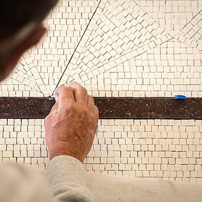 Craftsman laying a tile of white mosaic at Bulgari's Place Vendôme store, close up.
